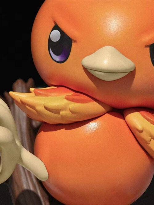 Close-up of Torchic's purple eyes, pale beak, layered yellow-orange feathers and raised foot.