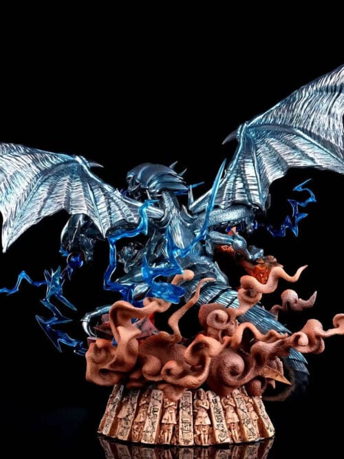 Rear view of Blue-Eyes Ultimate Dragon showing spread silver-blue wings, a segmented tail and curling dust effects above the carved base.