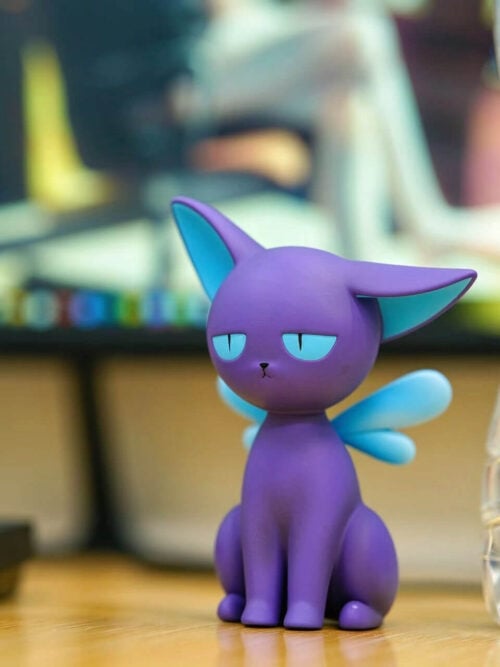 Purple Spinel Sun figure with pale blue wings seated on a desk beside a water bottle, with a keyboard at left.