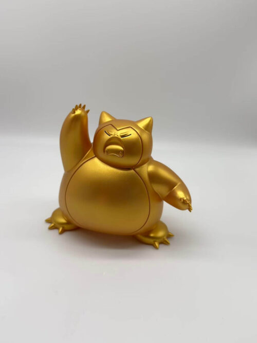 Gold-colored Snorlax figure viewed at a slight angle, with one arm raised, closed eyes and an open mouth.