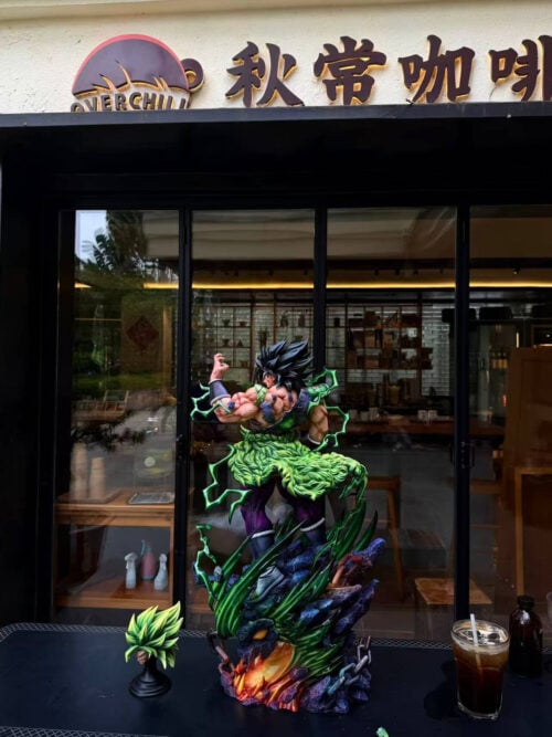 Full Broly statue with a black-haired head on a dragon-head base, beside a green-haired head displayed on a separate black stand.