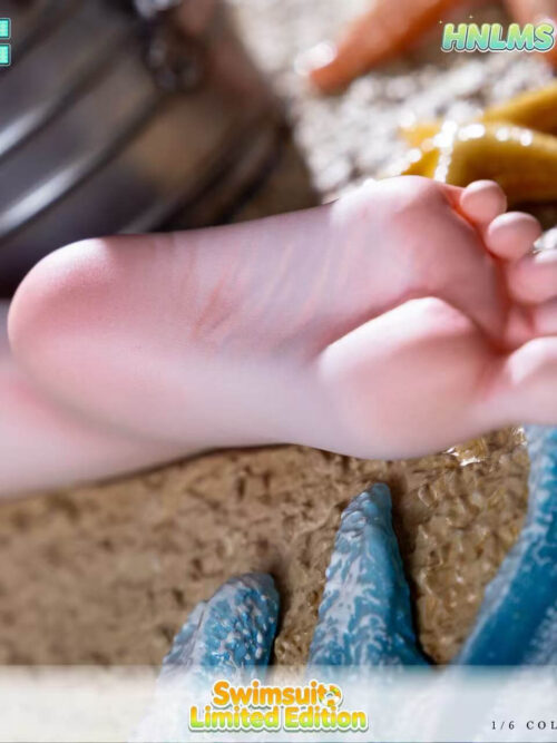 Horizontal close-up of the Gouden Leeuw statue's foot above textured sand, with blue waves, starfish and part of the bottle bucket.
