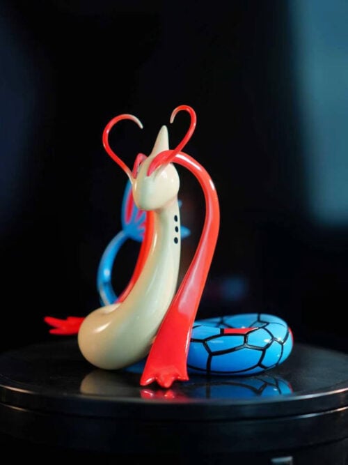 Three-quarter view of LD Studio's Milotic figure with long red head fins and a black-outlined blue tail on a black platform.