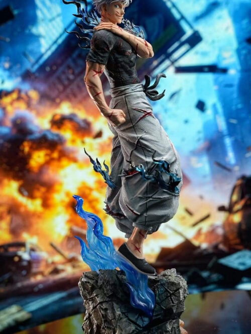Full-length Satoru Gojo statue with swept-up white hair, blue effects and a rocky base before a city explosion backdrop.
