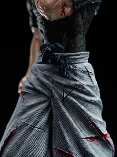 Detail of Satoru Gojo's cut-marked arm, textured black shirt, tied waist sash and torn gray trousers.