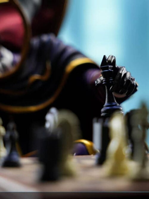 Close-up focused on Lelouch Lamperouge's black-gloved left hand holding a black king chess piece above blurred pieces on the board.