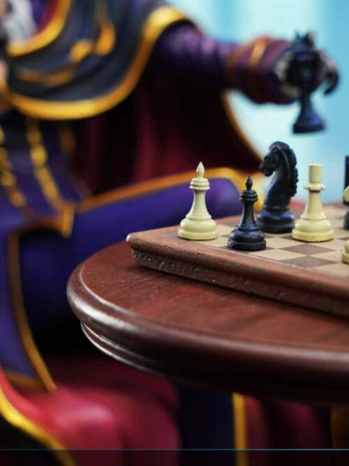 Close-up of the chessboard set on the round wooden table, showing black and white chess pieces in focus with Lelouch's gloved hand holding a black piece above.