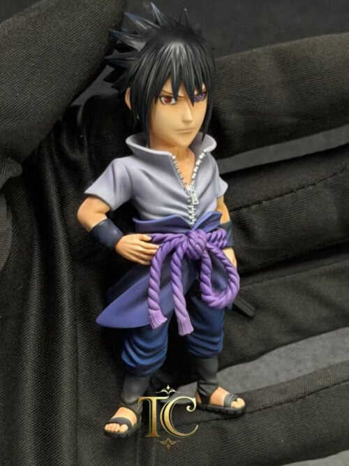 TC Studio Six Paths Sasuke Uchiha WCF Vol. 04 stylized figure held in a black-gloved hand, showing his right-eye Sharingan, left-eye Rinnegan, open zippered grey shirt, purple rope belt, and sheathed sword.
