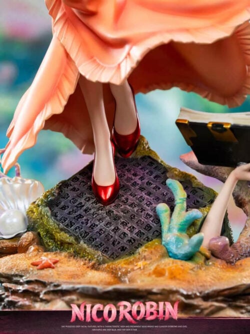 Close-up of the Deluxe Version reef base showing Nico Robin's red heels on a Poneglyph beside a pearl clam, coral, and a sprouted arm holding an open book