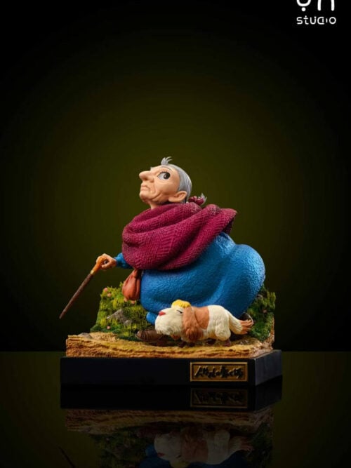 Left profile studio view of elderly Sophie leaning on her walking stick and looking upward beside Heen on a grassy dirt path base.