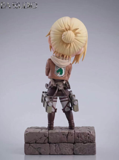 Rear studio view of BA Studio SD-scale Annie Leonhart figure on a cracked stone base showing her blonde hair bun, hood, Military Police unicorn emblem on the jacket back, and ODM gear