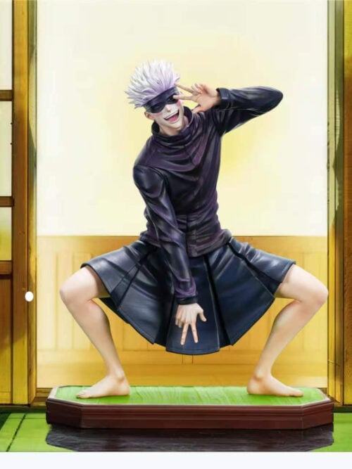 Firefly Studio Satoru Gojo Vol. 02 1/6 scale statue crouching barefoot in a dark high-collared jacket, black blindfold, and pleated uniform skirt on a green tatami-style base, flashing double peace signs in front of a promotional room backdrop.