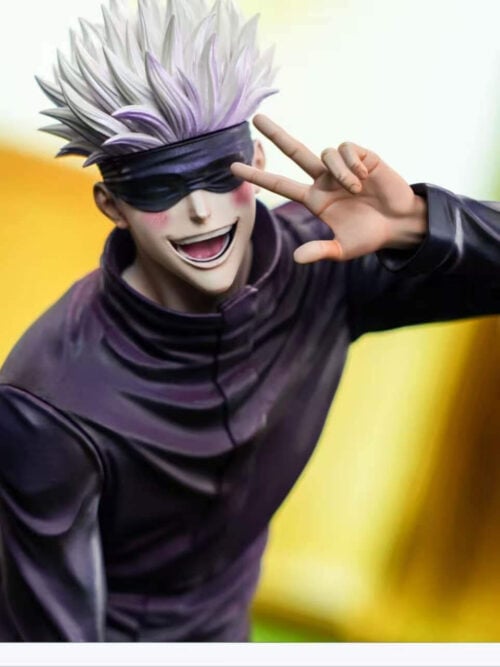 Close-up of Firefly Studio's Satoru Gojo Vol. 02 statue showing his spiky white hair, black blindfold, pink-blushed cheeks, wide open-mouthed grin, and left hand flashing a peace sign beside his face.