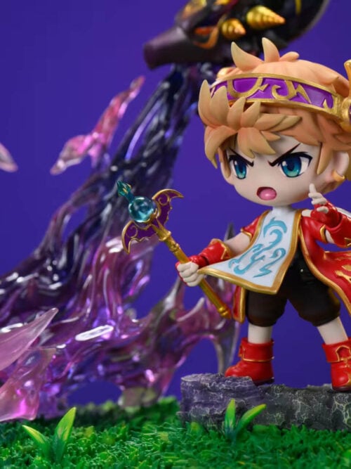 Close-up of the chibi Evan figure from MapleStory wearing a winged gold-and-purple circlet, red tunic, patterned white tabard, and red boots while holding a blue-orbed staff in front of purple flames.