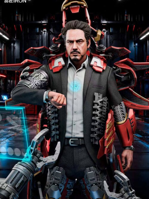 Promotional close-up of the IRON Studio Tony Stark Mark VII statue with a glowing blue chest Arc Reactor visible through his grey shirt and a workshop backdrop behind the open armor.