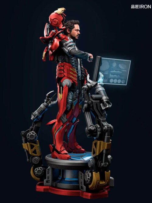 Right-side profile view of the IRON Studio Iron Man MQ70 Mark VII statue showing the open helmet and back armor behind Tony Stark, segmented red-and-gold leg armor, circular base, and angled blue data screen.