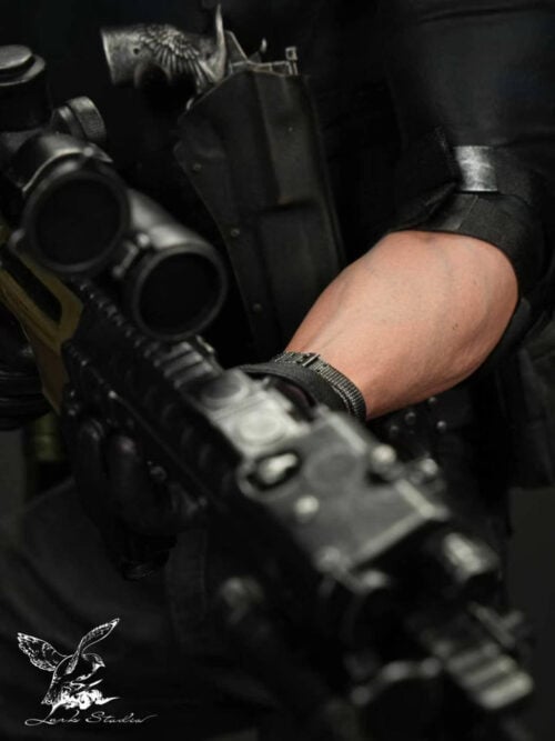 Close-up of Leon Scott Kennedy's left forearm with wristwatch, gloved hand gripping the rifle rail, rifle optic, and chest-holstered handgun with an ornate winged grip.
