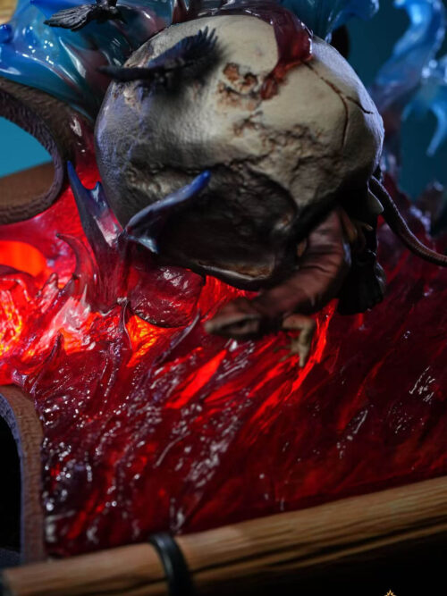 Close-up of the display base showing a cracked horned skull, small black birds, and illuminated red translucent crystalline effects on a scroll platform.