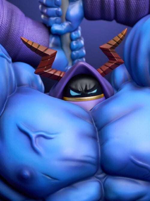 Extreme close-up of the small black face under a purple hood, with light-blue eyes and brown lightning-shaped horns, surrounded by the statue’s blue pectorals and raised wrapped arms.