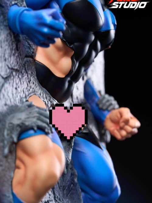 Close-up of the statue’s blue sleeve, black sculpted torso, and torn suit edges against rough gray stone, with a stone hand and a blue-gloved fist nearby. A pink pixel heart overlays the center.