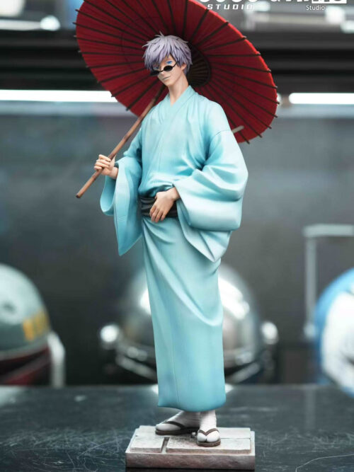 Adult Satoru Gojo 1/6 scale figure in a pale blue yukata with a red Japanese umbrella standing on a stone-textured square base on a studio display surface.