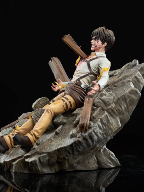 Left side view of the Eren Jaeger statue showing the angled rocky debris base, reclined pose, brown boots, and wooden beam piercing through his torso.